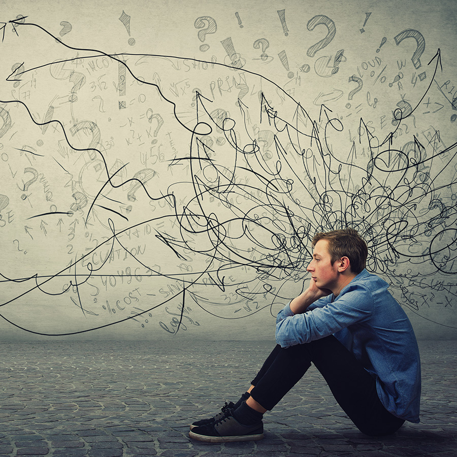 Man with depression and anxiety sitting on floor surrounded by thoughts