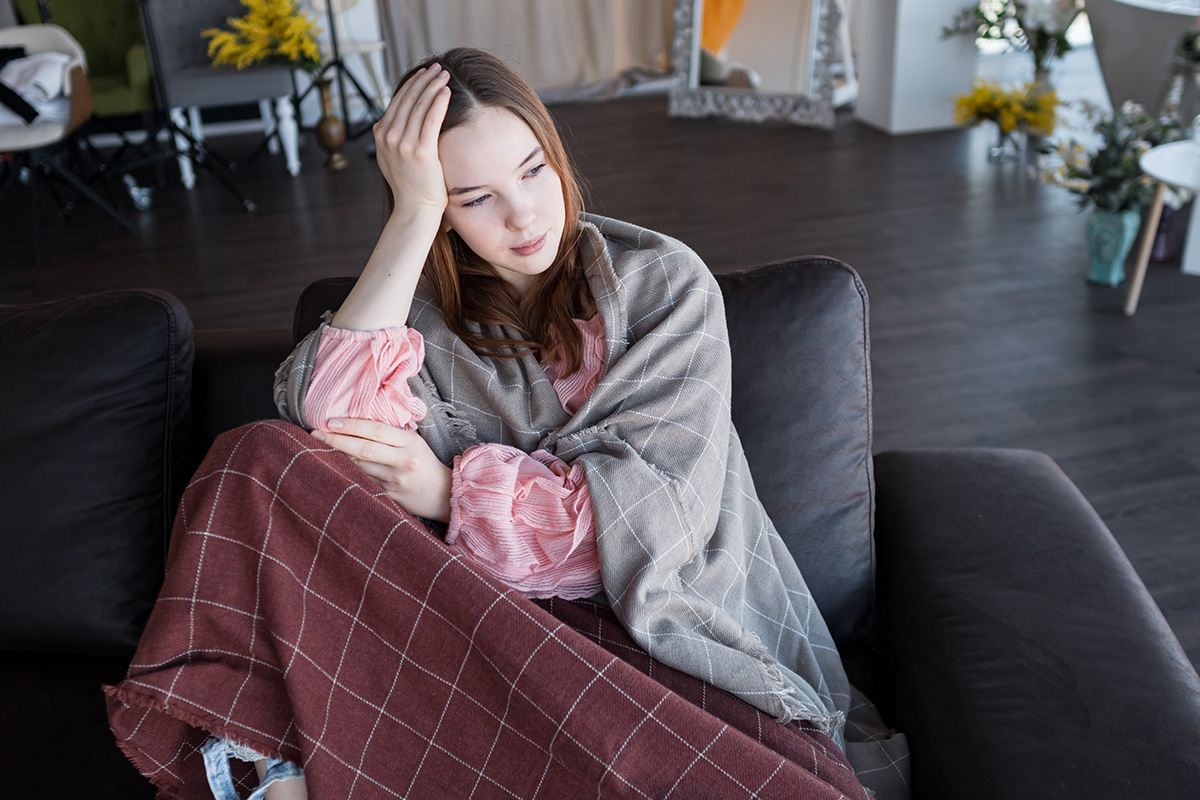 young woman sits in chair while physically ill and working on mental health