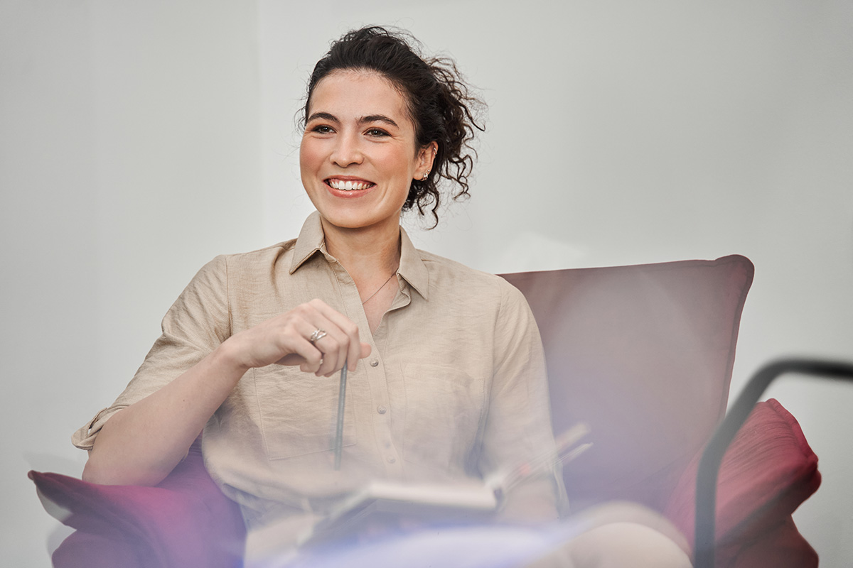 Woman sitting smiling with book about accelerated resolution therapy