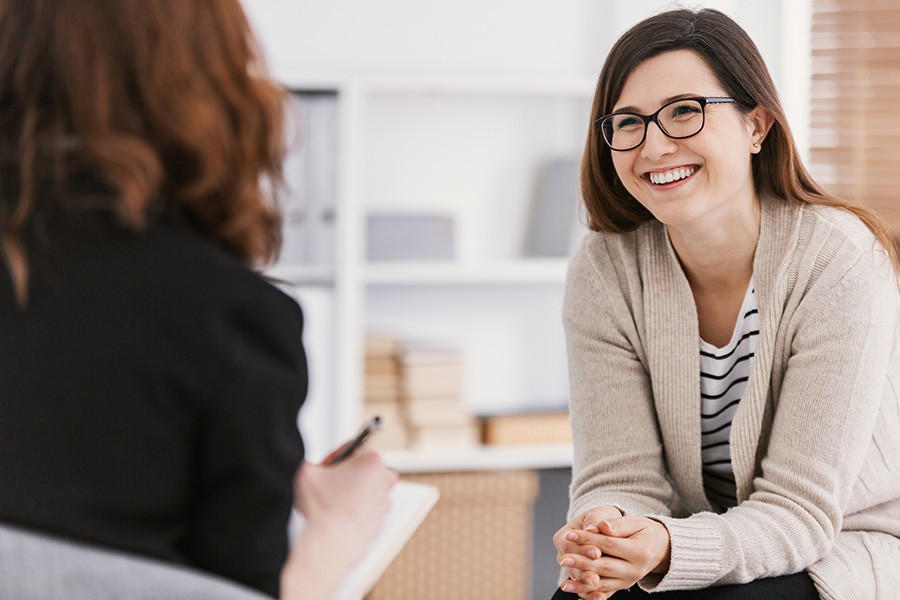 woman sitting with therapist while smiling and content, considering pausing therapy