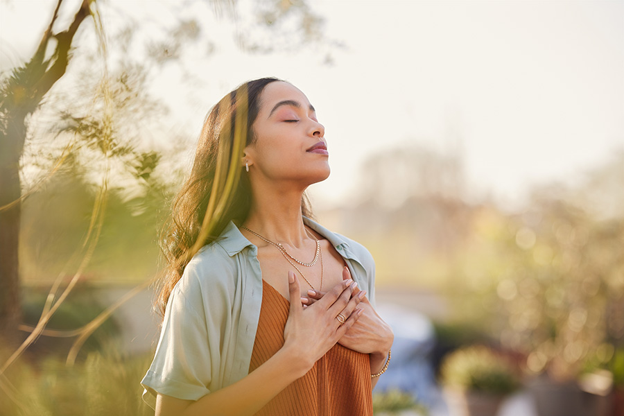 woman stands outside taking deep breaths to regulate nervous system